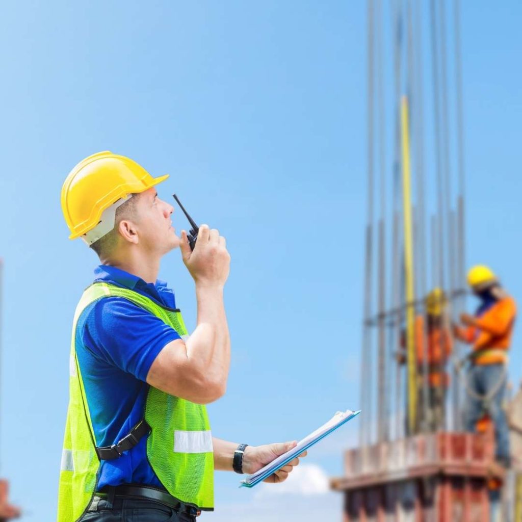 Man on a construction site using a walkie talkie to communicate