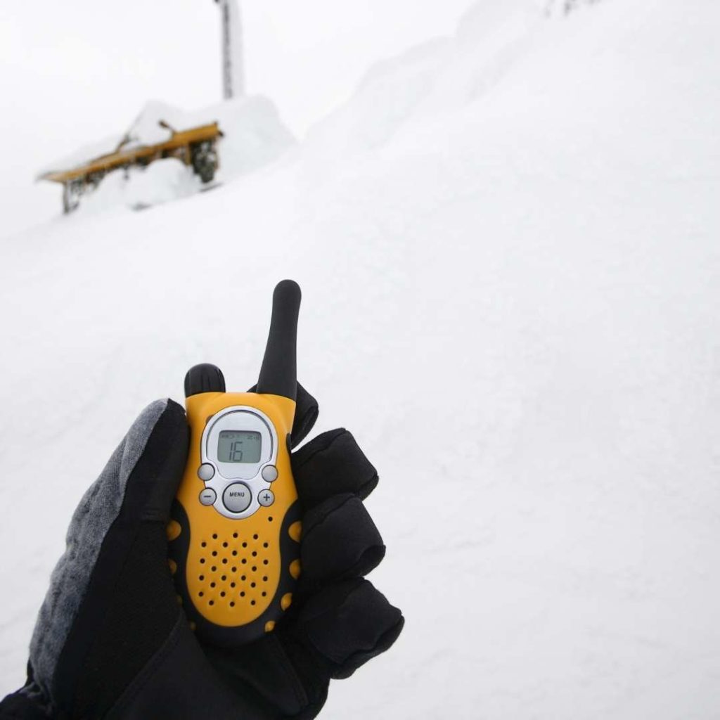 Man with ski gloves on using walkie talkie in snow