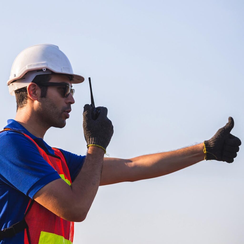 worker using a radio and giving a thumbs up