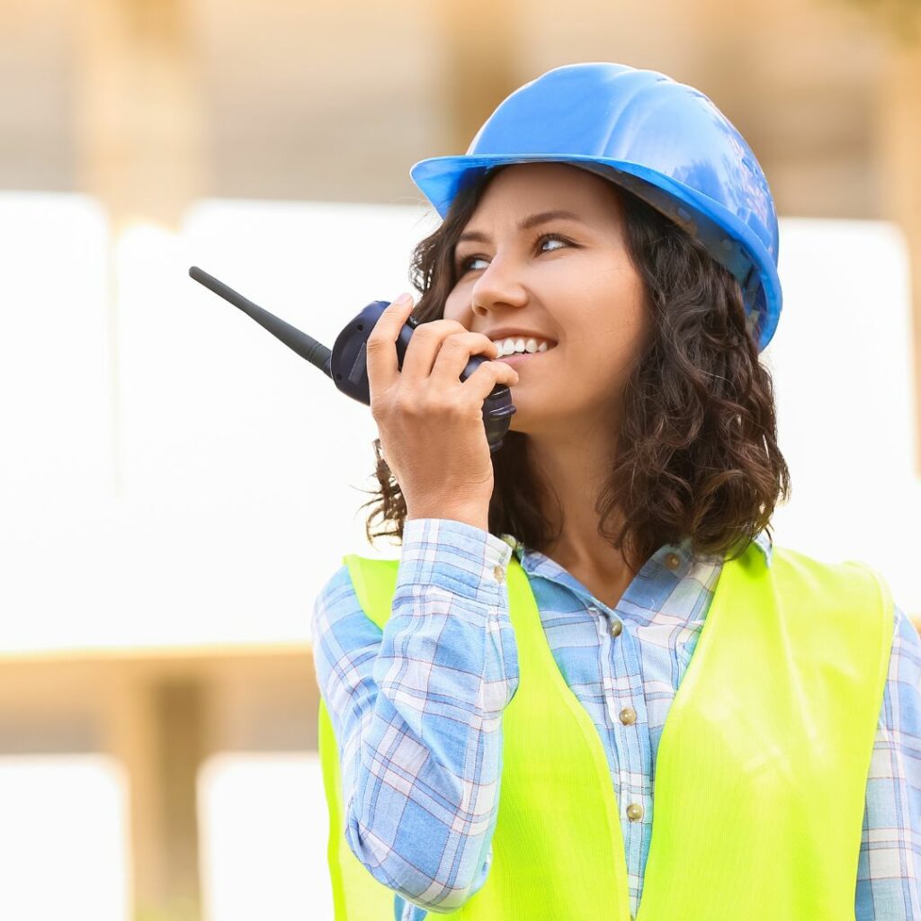 woman in high-vis vest talking into radio, smiling