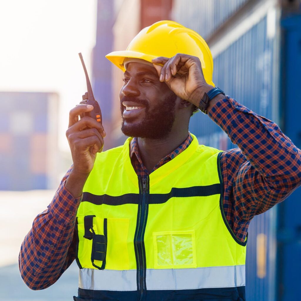 smiling working wearing a hard hat and using a radio