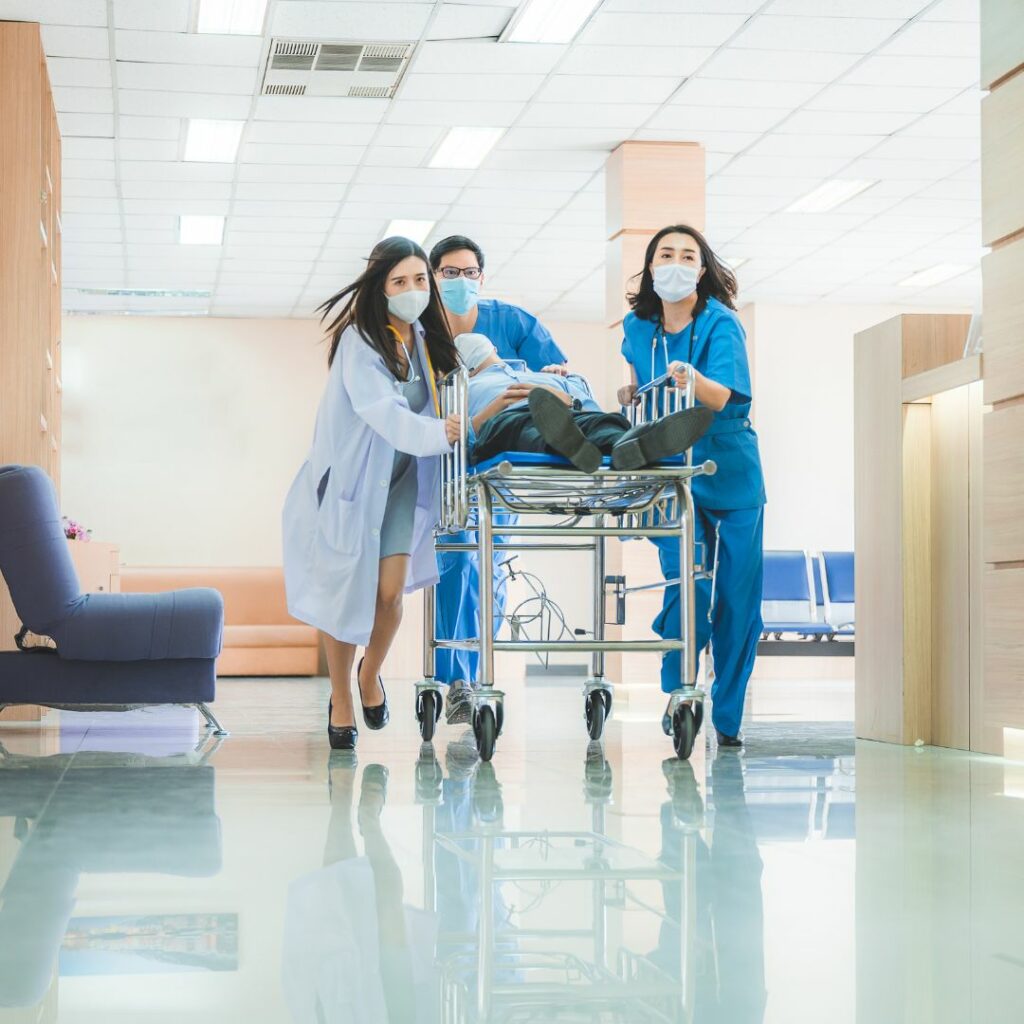 Healthcare professionals wheeling a patient urgently down a hall. 