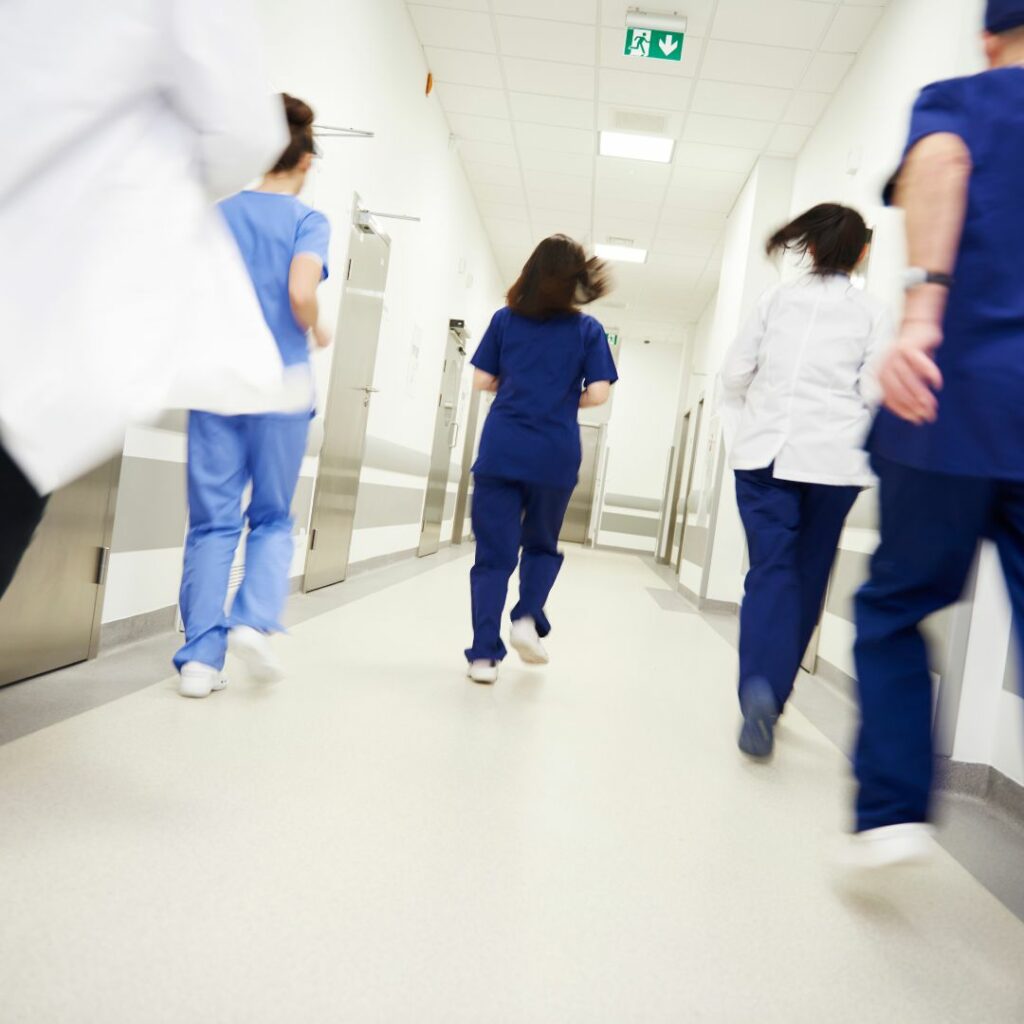 Team of nurses and doctors running down a hallway.