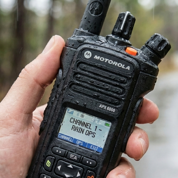 Close-up of rugged black two-way radio held outdoors in light rain